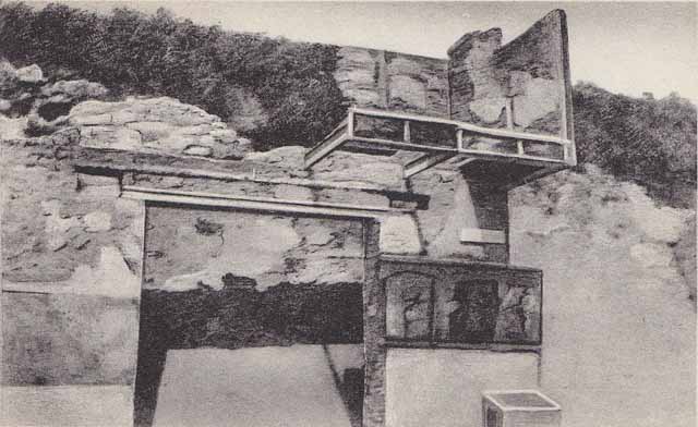 Street shrine outside IX.12.7. Detail from 1912 photograph. Top right of the four paintings was a painting of two Lares in green tunics leaning on pillars. A genius was making a sacrifice at a portable altar. Three other similar people from an older picture were also visible through the white background. See Fröhlich, T., 1991. Lararien und Fassadenbilder in den Vesuvstädten. Mainz: von Zabern. (p. 339, F71, T: 58,2).