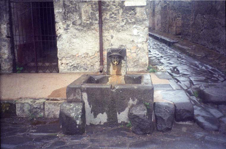 Fountain of Mercury at VI.8.24. 19th Century painting by D Capri of “Idealised city street scene”. This shows the fountain of Mercury and remains of street shrine painted on the wall at the rear. See Niccolini F, 1896. Le case ed i monumenti di Pompei: Volume Quarto. Napoli. (2 Taf A II).