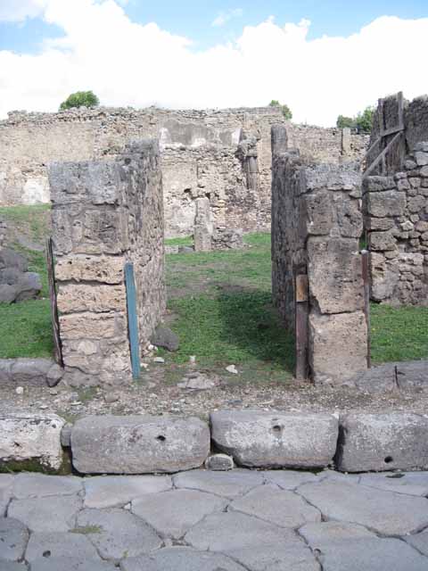 1.2.3 Pompeii. September 2010. Looking north towards remains of north wall (left or north-western corner of atrium). The shop at I.2.4 is on the left behind the wall. The north wall of house at I.2.6 can be seen at the rear. Photo courtesy of Drew Baker.