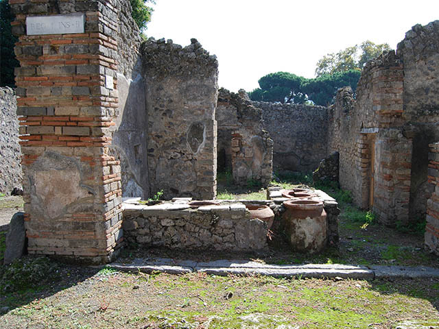 I.2.18 Pompeii. September 2005. Entrance. According to Della Corte, the bar was held by a greek named, Demetrios.  Painted graffiti was found on the left side of the entrance of number 18, underneath a big phallus leaning from the external wall:

L(ucium)  C(eium)  S(ecundum)  II vir(um)  o(ro)  v(os)  f(aciatis)
Demetrius rog.     [CIL IV 2993z].      

Demetrius (rogat)     [CIL IV 2993z, a]

On the right side of the entrance, a painted graffito was found with the name of his companion.  She was named Helpis, also greek, but possibly of african descent or brown in colour, as she was described by the name of Afra.  

L(ucium)  Ceium  Secundum  II vir(um)  o(ro)  v(os)  f(aciatis)
Helpis Afra rog(at)      [CIL IV 2993z, c]

See Della Corte, M., 1965.  Case ed Abitanti di Pompei. Napoli: Fausto Fiorentino. (p. 272)
