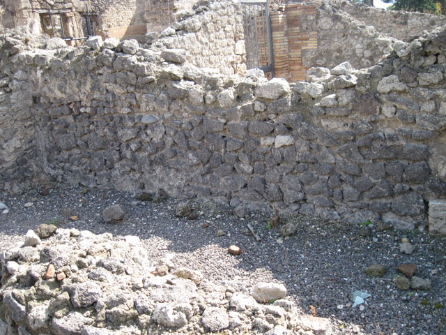 I.3.5 Pompeii. September 2010. Detail of niche in rear east wall on south side. Photo courtesy of Drew Baker. According to Boyce, this broad arched niche in the east wall, originally had its walls coated with white stucco. The stucco was painted with red, blue and green flowers and plants. Eventually, a layer of red stucco was spread over the top, and since peeling off, had revealed the earlier layer underneath. See Boyce G. K., 1937. Corpus of the Lararia of Pompeii. Rome: MAAR 14. (p.24) 
