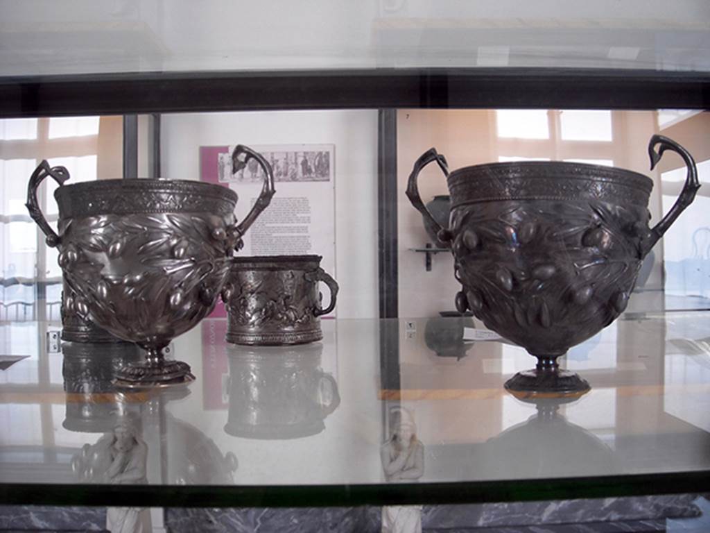 I.10.4 Pompeii. Two double handled calici - scyphi (at front), silver cups decorated with olives. Part of the 115 pieces of Silver found in a chest in the underground storerooms. Now in Naples Archaeological Museum. Inventory numbers 145514 and 145513. See Guzzo, P. (A cura di), 2006. Argenti a Pompei. Milano, Electa. p.204.
