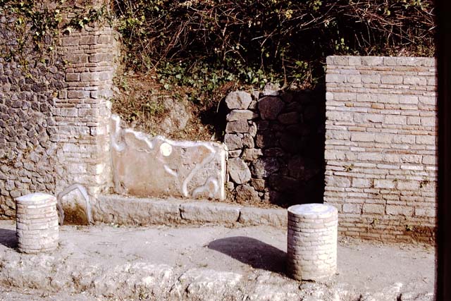 II.5.1 Pompeii. December 2006. The area to the right of the brick wall, where the modern sign post is now, was the site of pilaster of the gate that closed the Vicolo between II.5 and II.4  on the Via dell’ Abbondanza.  This was not restored after the bomb damage of 1943.  

