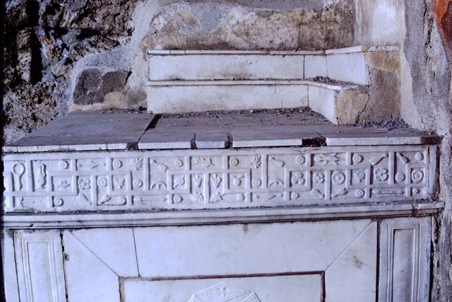 V.1.26 Pompeii. Mid 1880s. Detail from old photograph of items in storage. 
Marble slab from above the household altar in atrium.
Scene of the Castellum Acquae and Vesuvian Gate in the earthquake of AD62. 
