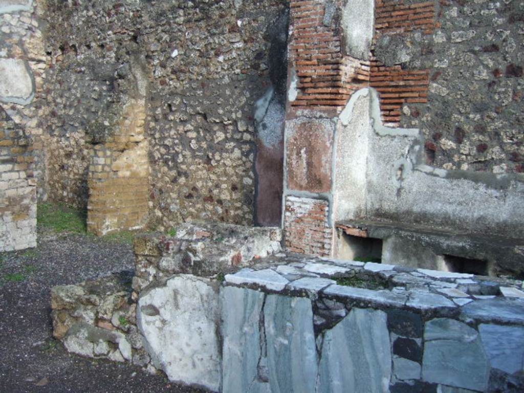 VI.3.20 Pompeii. December 2005. Counter with hearth at end. According to Dyer:
At the angle of two streets, just behind the fountain, was a small shop, called by some a thermopolium, or shop for the sale of hot drinks. The walls were gaudily painted in blue panels with red borders, and towards the street was a counter cased with marble. The stains left on these counters, apparently by wet drinking-glasses, have led to the identification, or supposed identification, of several such shops.
See Dyer, T., 1867. The Ruins of Pompeii. London: Bell and Daldy.  (p.49)
According to Breton: This bar of Fortunata had a counter of masonry which held several large terracotta containers, and was covered with a marble tablet, where the footprints of cups/glasses could still be recognised. The liquids contained in them must have contained some acid principle which had attacked the polish of the marble. At the rear was a higher area which held the brazier for heating various beverages.
See Breton, E; Pompeia, decrite et dessine, 1855, (p.219)
