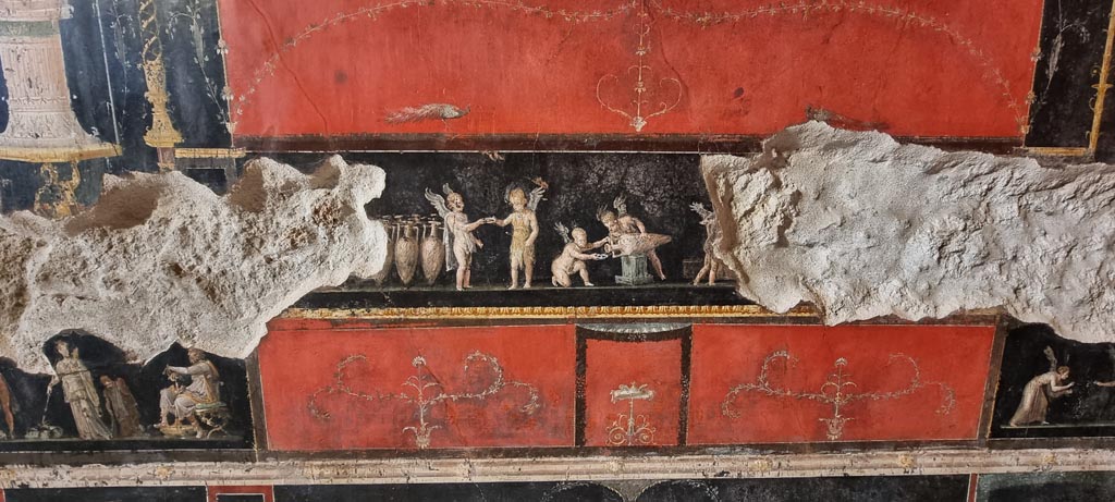 VI.15.1 Pompeii. January 2023. 
Central panel in predella on west wall, with painting of cupids buying and selling wine. Photo courtesy of Miriam Colomer.

