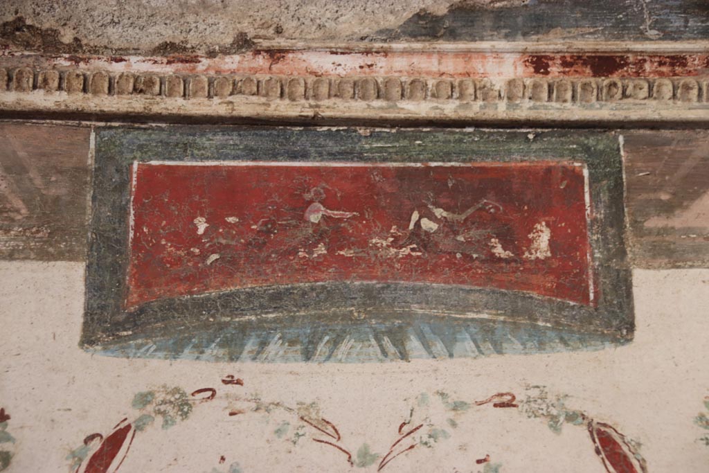 VI.15.1 Pompeii. October 2023. 
Detail of painted panel from above the central “removed” missing painting on east wall. Photo courtesy of Klaus Heese.

