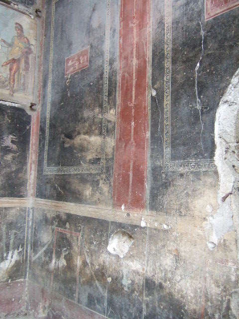 VI.15.1 Pompeii. December 2006. North-west corner of vestibule with painting of a bearded Priapus.
It seems to suggest good health is worth its weight in gold. A large basket of fruit represents the abundance of the house.

