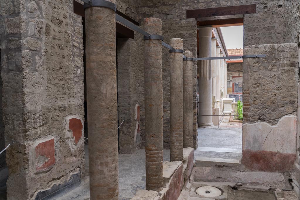 VI.15.1 Pompeii. March 2023. Looking south across courtyard “s” towards doorway to large peristyle “m”, centre right. 
The doorway on the left is into the cubiculum “u”. The doorway in the centre, behind the column, is into the triclinium “t”.
Photo courtesy of Johannes Eber.

