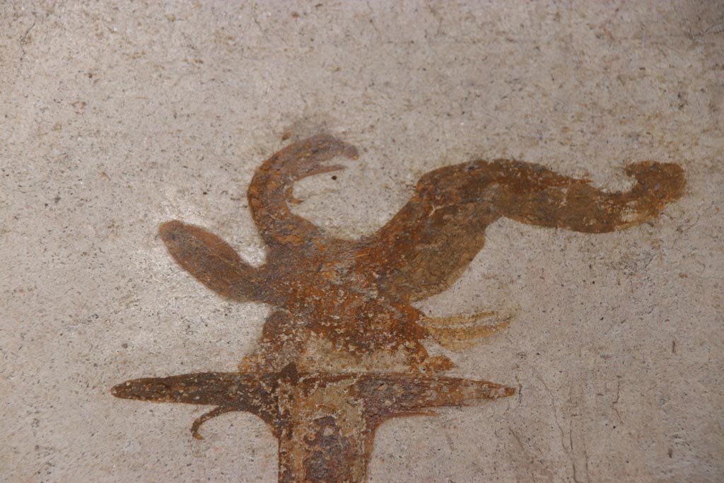 VI.15.1 Pompeii. October 2023. 
North wall of small courtyard/peristyle garden “s”, detail of painted eagle from top of candelabra. Photo courtesy of Klaus Heese.
