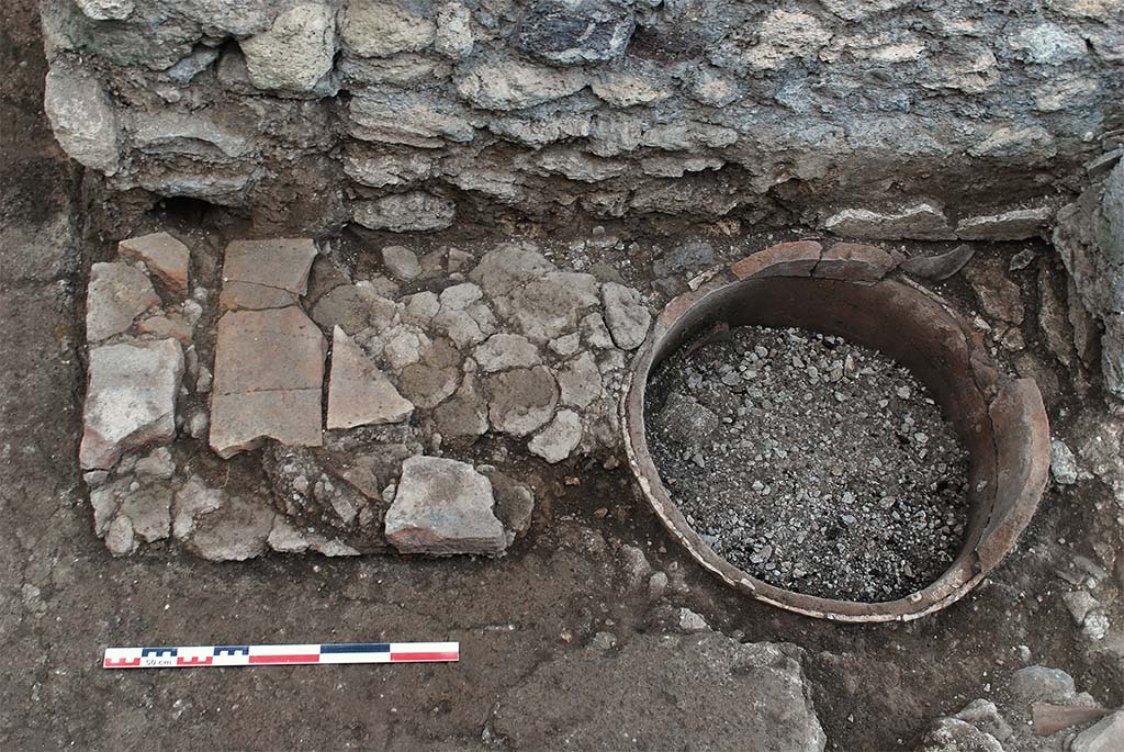 Fig. 14 – Pompéi, boulangerie VII 2, 3.6-7 – dolium inséré dans le sol de la salle de façonnage et accolé à un massif maçonné.
Pris de l’ouest. Cliché : P. Larrieu /EFR.
