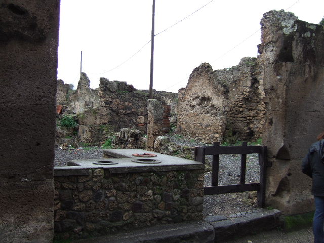 VII.6.20 Pompeii. March 2009. Looking west across sales-room with two sided counter with 3 urns and a hearth. 
According to Della Corte, this small dwelling annexed to another caupona was lived in by a pompeian, known only by the initials M. C. N.
Written on the dado of an internal rooms was - M. C. N. pecunia  sua  f(e)c(it)     [CIL IV 495]  See Della Corte, M., 1965.  Case ed Abitanti di Pompei. Napoli: Fausto Fiorentino. (p.173)
According to Epigraphik-Datenbank Clauss/Slaby (See www.manfredclauss.de), this read
M(arcus)  C()  N()  pecunia  sua      [CIL IV 495]
