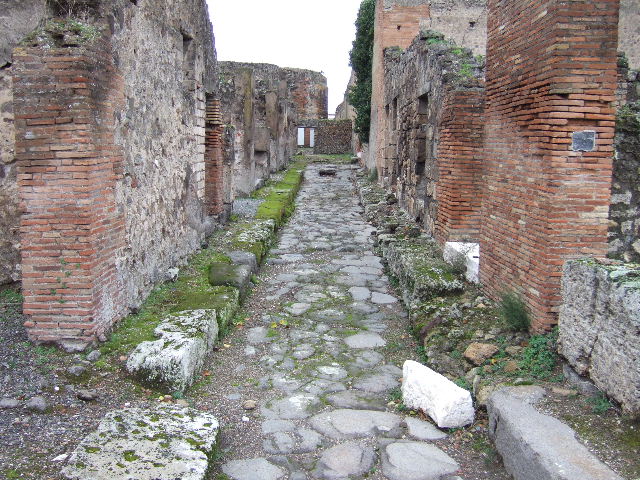 VI.9.37 Pompeii. December 2005. Entrance doorway on Vicolo del Balcone Pensile, with a podium on the left. Looking north into VII.9.36 and to doorway to latrine in north wall, under the stairs at VII.9.35