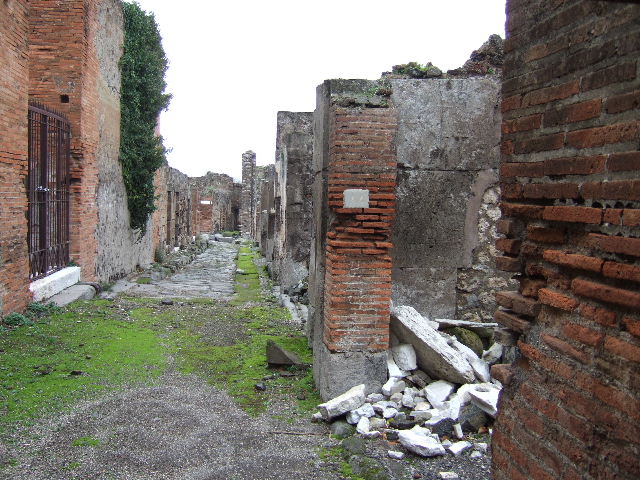VII.9.44 Pompeii. December 2005. Looking south across workshop. On the left would have been a stairs to an upper floor with remains of wash-basins beneath. In the rear room, there would have been a podium with three kettles or boilers, a hearth and nearby a basin.
