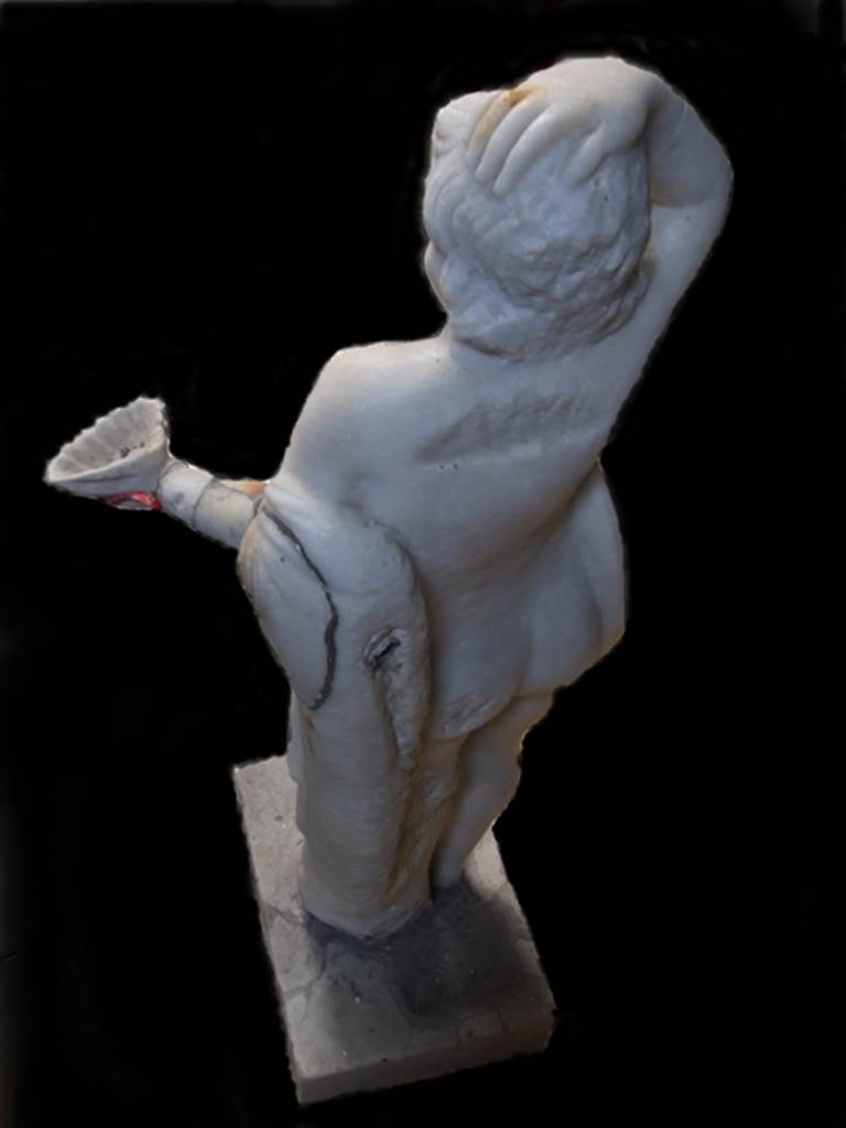 VII.12.28 Pompeii.  Marble fountain statue of small boy with hand on head and holding a shell.  Rear view showing pipework into arm.  SAP inventory number 20395.