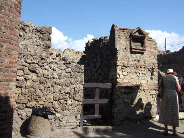 VII.16.6 Pompeii. September 2004. Looking north across workshop, at the rear was a doorway into VII.16.9. According to Eschebach, the doorway on the left would have led into a small room under the steps at VII.16.5.
At the rear on the left would have been a stairs to the upper mezzanine, with a latrine beneath. In the workshop were two dolia, three mortars, and two or three mills.
See Eschebach, L., 1993. Gebäudeverzeichnis und Stadtplan der antiken Stadt Pompeji. Köln: Böhlau. (p.347)