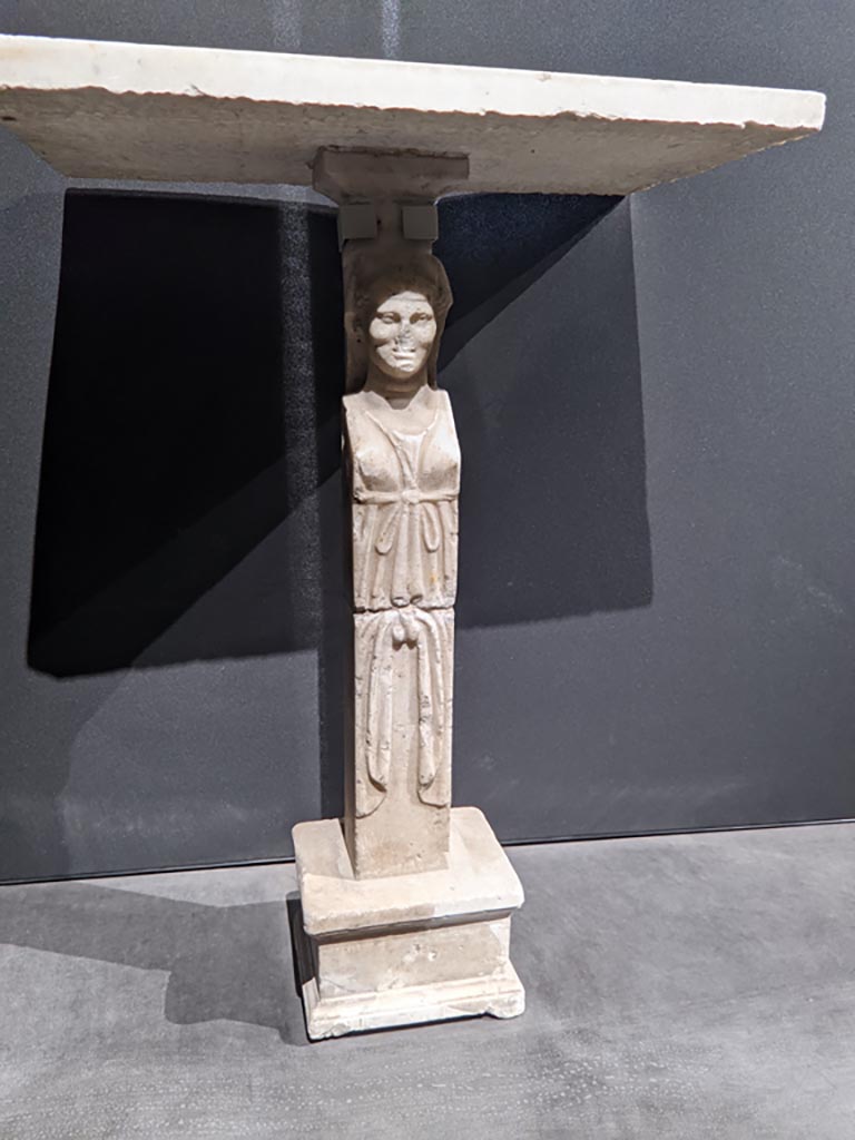 VIII.1.4 Pompeii. April 2022. 
Foot/leg of a table, on display in exhibition in the Palaestra. Photo courtesy of Giuseppe Ciaramella.
Could this be one of the monopodiums for supporting a table, as mentioned by Fiorelli, in either -
Fiorelli, G., 1897. Guida di Pompei, (p.110).
Fiorelli, G., 1877. Guida di Pompei. (p.108).
(for details of these pages, see VIII.1.4, part 5).
