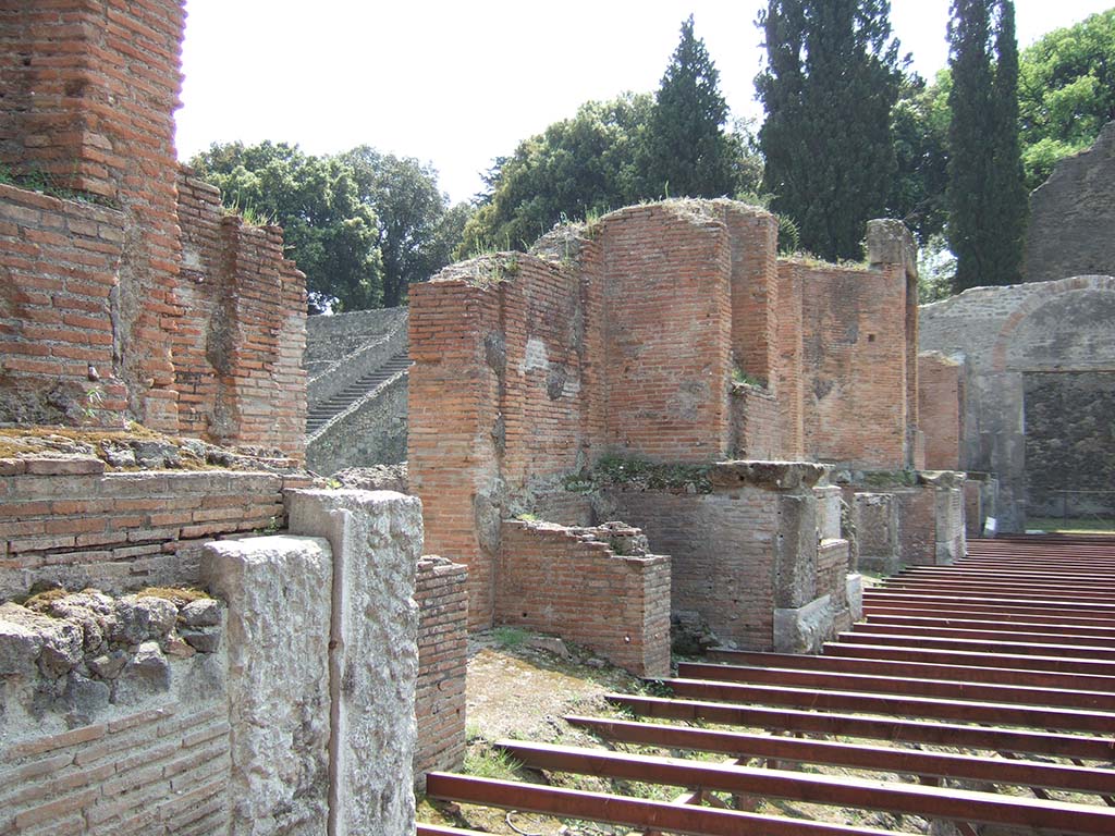 VIII.7.20 Pompeii. May 2006. Looking south-west across site of stage. 
According to Cooley:
The Holconii (two brothers, or perhaps less likely father and son) greatly increased the theatre seating capacity.
They added a new upper section of seating supported by vaulted passageways, or a crypt. 
They also created two privileged areas of seating, or boxes, over the covered corridors leading into the orchestra from either side of the theatre. 
There were multiple inscriptions recording the benevolence of Marcus Holconius Rufus and Marcus Holconius Celer.
These were set up in different parts of the theatre including two identical inscriptions, each well over 6 metres long, in the area of the stage.

MM(arci) Holconii Rufus et Celer cryptam tribunalia thea[trum] s(ua) p(ecunia)    [CIL X 833]
MM(arci) Holco[nii] Rufus et Celer [cryp]tam tribunalia theatrum s(ua) p(ecunia)    [CIL X 834]

Marcus Holconius Rufus and Marcus Holconius Celer built) at their own expense the crypt, boxes and theatre seating.

See Cooley, A. and M.G.L., 2004. Pompeii: A Sourcebook. London: Routledge. p. 67.
