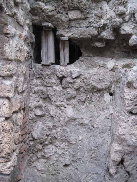 VIII.7.23 Pompeii. September 2010. South wall with entrance, leading to a long, narrow room. Photo courtesy of Drew Baker. This is most likely the remains of the doorway to the kitchen and perhaps a storeroom, on the south side of the shop. The other wall, in the background, is the south wall of VIII.7.22.