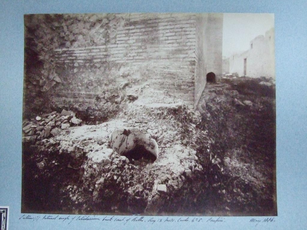 IX.4.18 Pompeii. Central Baths. May 1886. Cisterns (?) at external angle of caldarium “s”, back court “t” of Baths. 
Courtesy of Society of Antiquaries. Fox Collection.
Looking north along east side. The internal side of open area “u” and doorway at IX.4.16 can be seen in the wall on the right.
According to Mau,
“Another large pilaster (1,50 x 1,20) was in the SE corner; it being built of grey tufa cut to look like masonry bricks – construction  that in these baths was not found anymore - so it would seem possible that it might be the remains of an older buildings; as one recognises with great certainty the opening of a cistern, conserved between this pillar and the corner of the caldarium”. 
See Bullettino dell’Instituto di Corrispondenza Archeologica (DAIR), 1878, (p253 of pages 251- 254). 
See IX.4.15.
