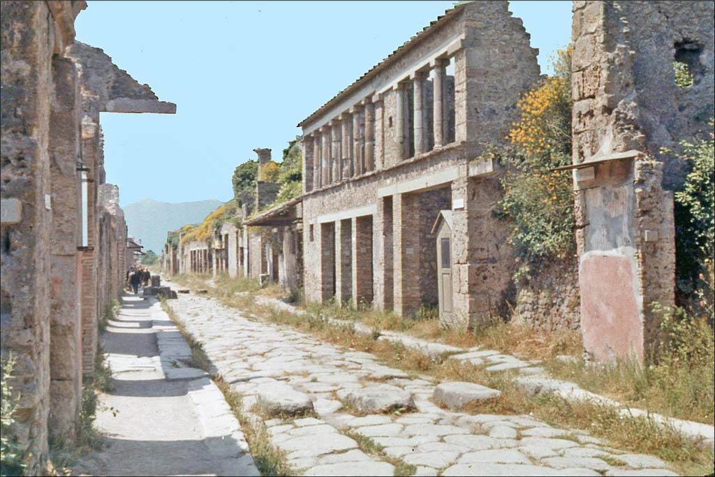 Via dell’Abbondanza, Pompeii. June 1962. Looking east between IX.12 and 1.8, from near IX.11.8, on left
Photo by Brian Philp: Pictorial Colour Slides, forwarded by Peter Woods
(P43.14 POMPEII House facades along a principal street)
