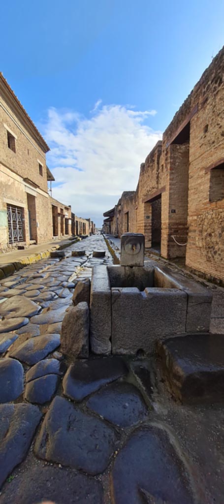Via dell’Abbondanza, Pompeii. April 2022.
Looking east to fountain in roadway between IX.13 and I.9. 
Photo courtesy of Giuseppe Ciaramella.
