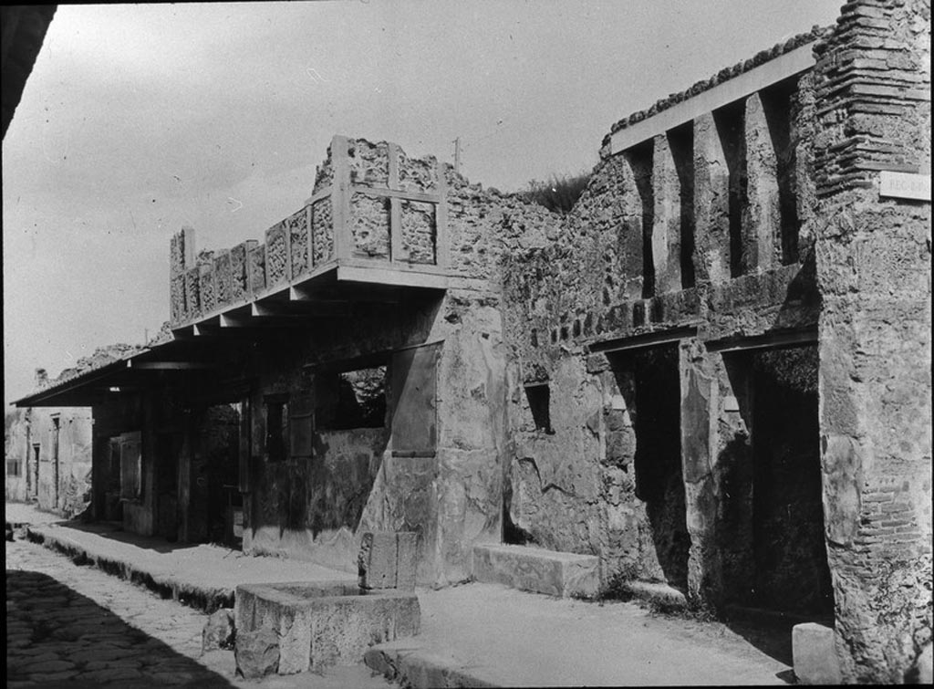 Via dell’Abbondanza, south side. Looking east from near I.12.1/2, on right.  Entrances on Via dell’ Abbondanza, with fountain outside. 
Photo by permission of the Institute of Archaeology, University of Oxford. File name instarchbx202im 001. Resource ID. 44520.
See photo on University of Oxford HEIR database
