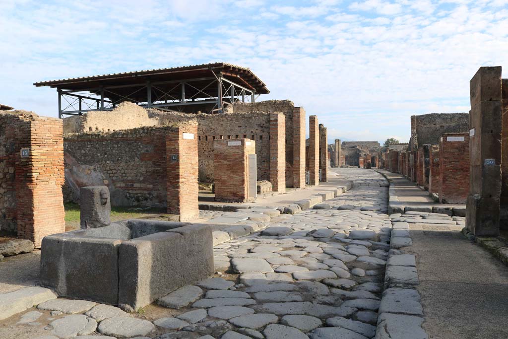 Via dell’Abbondanza, Pompeii. December 2018. 
Looking east from fountain at VII.14.14, towards junction of Vicolo del Lupanare, on left, and Via dei Teatri, on right. 
Photo courtesy of Aude Durand.

