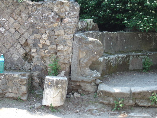 HGW02 Pompeii. 1793 painting with tomb on left showing the tufa block on the back of the schola. On the 16th March 1763 a marble plaque was found set in the tufa block. This had the inscription

A VEIO M F IIVIR I D
ITER QVINQ TRIB
MILIT AB POPUL EX D D

Now in Naples Archaeological Museum. According to Epigraphik-Datenbank Clauss/Slaby (See www.manfredclauss.de) this read
 
A(ulo) Veio M(arci) f(ilio) IIvir(o) i(ure) d(icundo)
iter(um) quinq(uennali) trib(uno)
milit(um) ab(!) popul(o) ex d(ecreto) d(ecurionum)      [CIL X 996]

According to Cooley this translates as 

To Aulus Veius, son of Marcus, duumvir with judicial power twice, quinquennial, military tribune by popular demand. By decree of the town councillors.

See Kockel V., 1983. Die Grabbauten vor dem Herkulaner Tor in Pompeji. Mainz: von Zabern. (p. 51). See Cooley, A. and M.G.L., 2004. Pompeii : A Sourcebook. London : Routledge. (p. 139, G4).