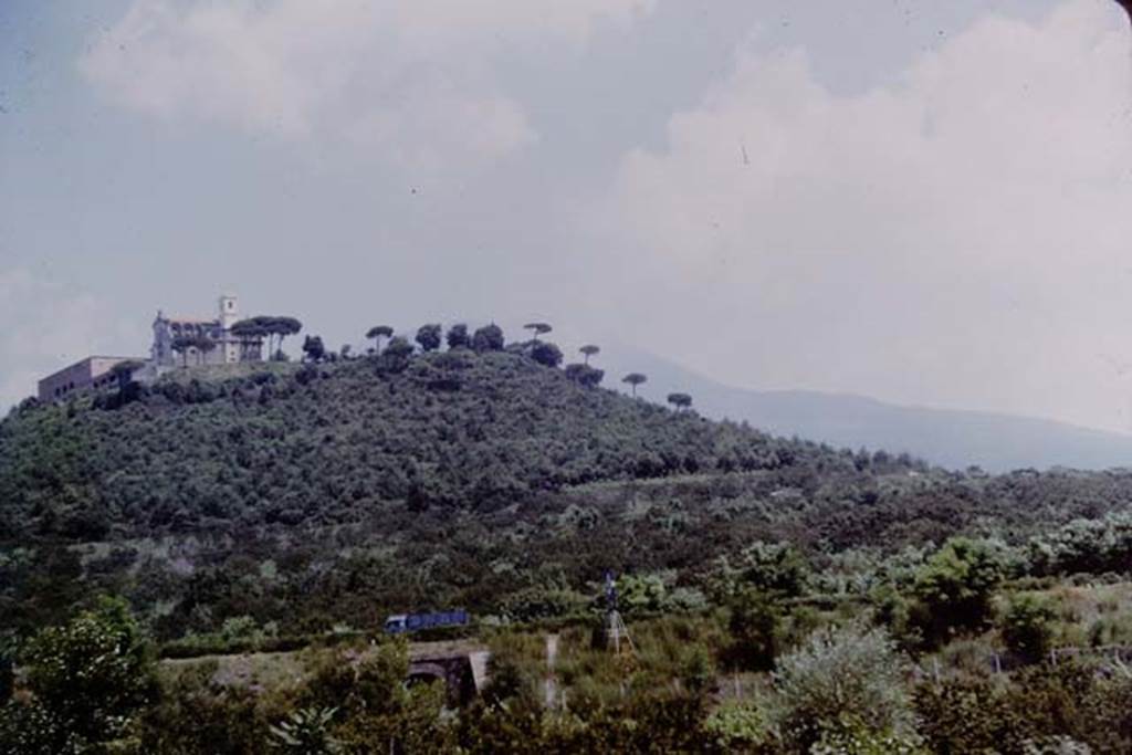 Missionari Redentoristi Colle Sant'Alfonso. 1964. Photo by Stanley A. Jashemski.
It sits on a hill of volcanic origin, S. Maria La Bruna, 185 metres high with Vesuvius behind to the north.
According to the church web site “the hill has suffered little from the devastating effects of nearby Vesuvius, from which a large valley separates it, enough to protect it from lava eruptions”. 
The hill and church are a very prominent landmark to anyone travelling along the A3 autostrada who looks north towards Vesuvius.
Source: The Wilhelmina and Stanley A. Jashemski archive in the University of Maryland Library, Special Collections (See collection page) and made available under the Creative Commons Attribution-Non-commercial License v.4. See Licence and use details.
J64f1138
