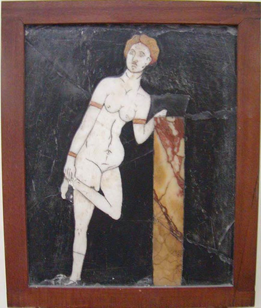 I.2.10 Pompeii. Found in triclinium.
Black crystalline rock adorned with opus sectile tablet of Venus untying, or doing up, her sandal.
Now in Naples Archaeological Museum. Inventory number: 109678.
According to Fiorelli, the triclinium was adorned with paintings that were now non-existent, other than a tablet of schist inserted into the wall.
On the tablet was mounted a marble figure of Venus untying her shoes.
See Pappalardo, U., 2001. La Descrizione di Pompei per Giuseppe Fiorelli (1875). Napoli: Massa Editore. (p.35)
According to Warscher, quoting Olga Elia (Bollettino d’arte, 1929, p.276) –
“Di due pannelli decorativi pompeiani con figure in “opus sectile” ad intarsio”
“Qui ci troviamo dinanzi ad un lavoro di ordine inferiore, di valore estetico negativo, per il rendimente del tipo e la trascuratezza della tecnica……….
Aggiungo qui un quadretto di opus sectile rinvenuto nella casa 10, of Insula 2, Regione I: vi è rappresentata su fondo nero di pietra di Genova una Venere in marmo bianco, che con capelli e braccialetti di marmo giallo, appoggiandosi con la sinistra ad un pilastrino, solleva la gamba sinistra per porsi al piede un armillo”.
See Warscher T., 1935. Codex Topographicus Pompeianus: Regio I.2. (no.22a), Rome: DAIR.