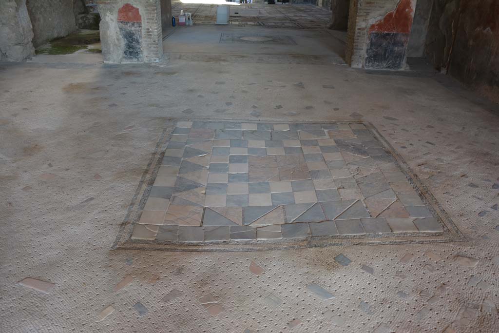 I.7.1 Pompeii. October 2019. Flooring in oecus, looking south across tablinum towards atrium.
Foto Annette Haug, ERC Grant 681269 DÉCOR.
In the centre of the floor of the oecus was an emblema in opus sectile of coloured marble.
This was made from square tiles with contrasting triangles and edged with a double black mosaic band.