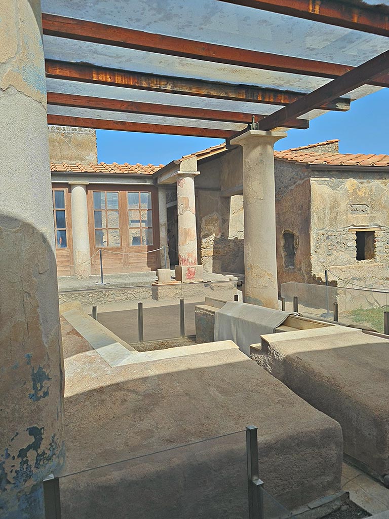 I.7.12 Pompeii. September 2024.
Looking north-east across triclinium in garden towards north portico and windows from cubiculum, on right.
Photo courtesy of Giuseppe Ciaramella.