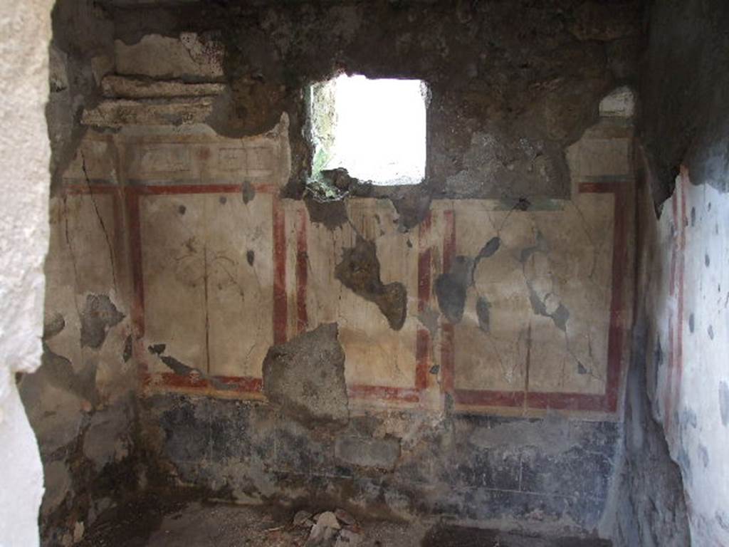 I.7.19 Pompeii. December 2006. West wall of cubiculum in south-west corner of atrium.
The zoccolo was black and consisted of a plinth with panels above: the middle zone of the wall consisted of white panels with a red border. The floor of this room was cocciopesto, the threshold was indicated by a “net” design of white tesserae in squares surrounded by black tesserae, whereas the anteroom and the alcove were with a series of regularly spaced white stone dots in lines. The floor of the passage between the anteroom and the alcove was of black tesserae. According to PPM, shown in the photos of 1977 and 1980, there was a sliding door on the window onto the vicolo in this wall. It was restored after the excavation, and can be seen in our photo of the south wall, leaning against the wall and no longer in its position on the window of the west wall.