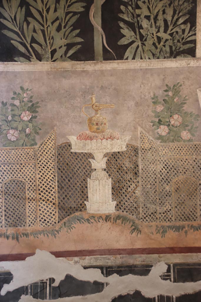I.9.5 Pompeii. October 2022.
Room 11, centre of east wall of cubiculum with garden painting with lattice fencing and table with Isis jug or jar.
Photo courtesy of Klaus Heese.