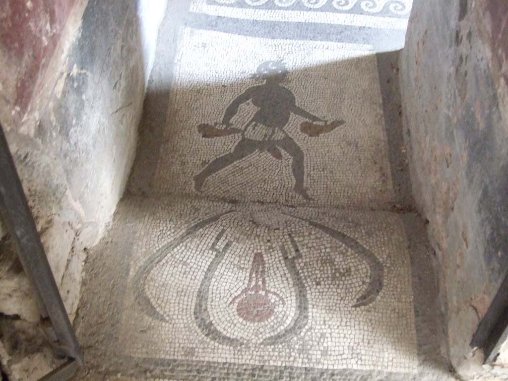 I.10.4 Pompeii. May 2006. Doorway to room 48, mosaic of figure carrying two askoi.
An askos was an ancient Greek pottery vessel used to pour small quantities of liquids such as oil.