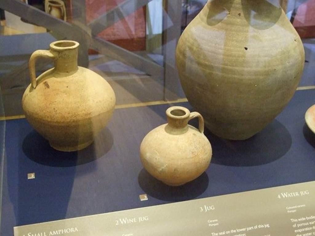 I.10.4 Pompeii. Small ceramic jug (at centre front). SAP 4981. The seal on the lower part of this jug bears the inscription, CN. ATEIUS ARRETINUS, LIBERTUS A ATEIO. It refers to Arretinus, a freedman (former slave) whose pottery business was operated in the town of Ateio around 30-40 BC. Photographed at “A Day in Pompeii” exhibition at Melbourne Museum. September 2009.