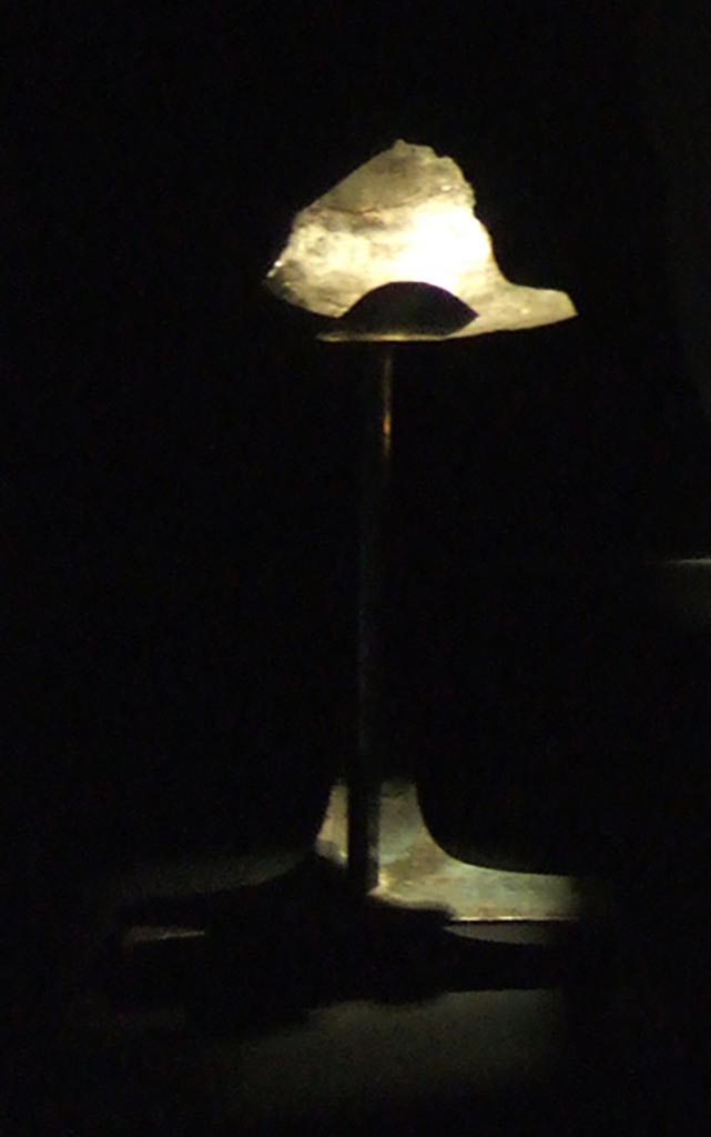 I.10.4 Pompeii.
Support stand for display of silver phiale or flat drinking vessel with gold emblem.
The stand has a triangular three footed base, a tall stem, and a moulded upper arm in which the phiale was inserted.
Part of the 115 pieces of Silver found in a chest in the underground storerooms.
Now in Naples Archaeological Museum. Inventory number 1445545.
See Guzzo, P. (A cura di), 2006. Argenti a Pompei. Milano, Electa. p.220-1.