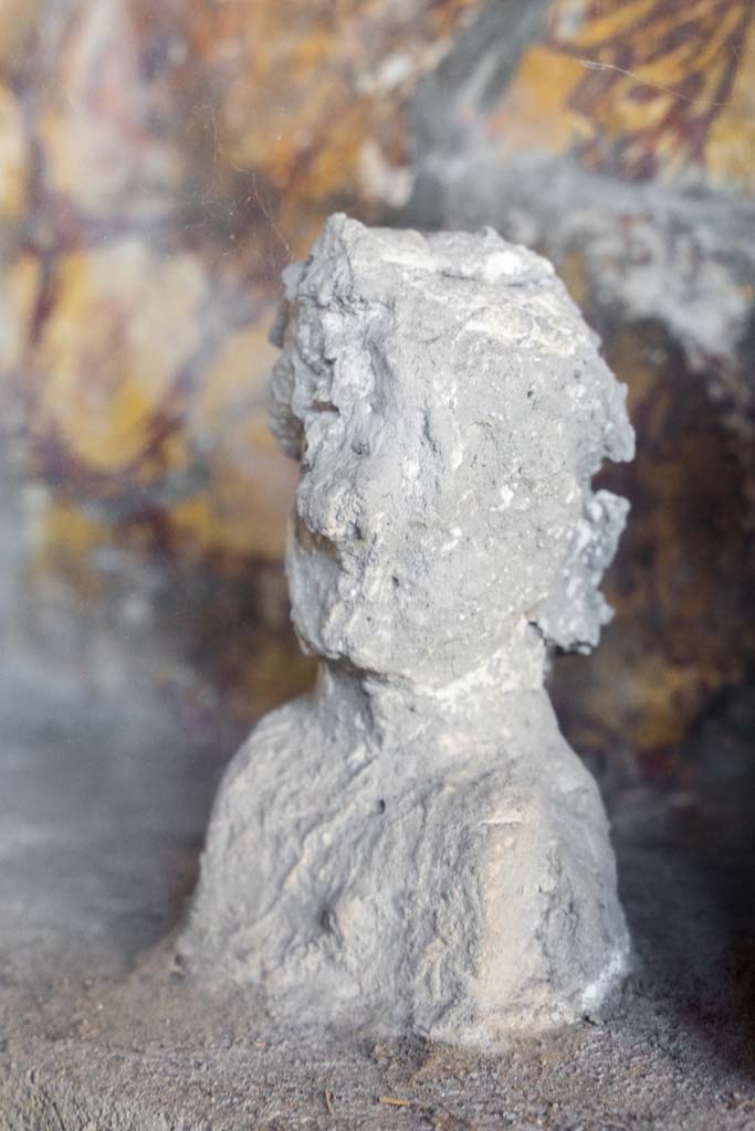 I.10.4 Pompeii. April 2022.
Alcove 25, detail of plaster cast, on the left, on the lararium or domestic shrine. (Image 2).
Photo courtesy of Johannes Eber.