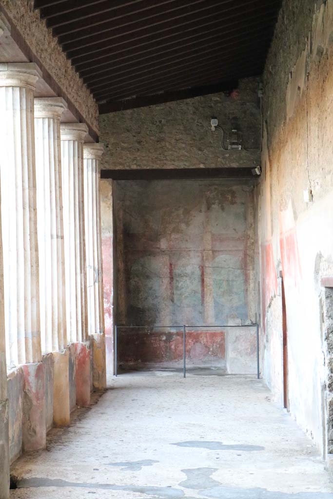 I.10.4 Pompeii, December 2018.
Looking south along west portico to Sacrarium with built in altar and apsed niche.
The walls have painted columns and pilasters opening onto a painted garden with trees and birds.
Photo courtesy of Aude Durand.