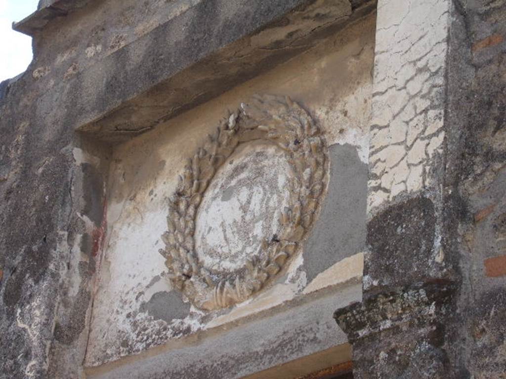 II.2.4 Pompeii. September 2005. Above the entrance doorway, one can still see the Augustan emblem. This is a crown of oak between two laurel branches. 


