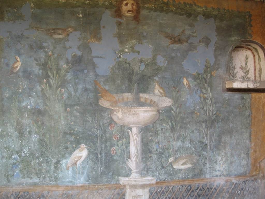 II.3.3 Pompeii. July 2007. Room 11, detail from west panel of south wall of peristyle.
Wall painting of fountain with garden, mask and birds. Photograph courtesy of Kathryn Breen.
