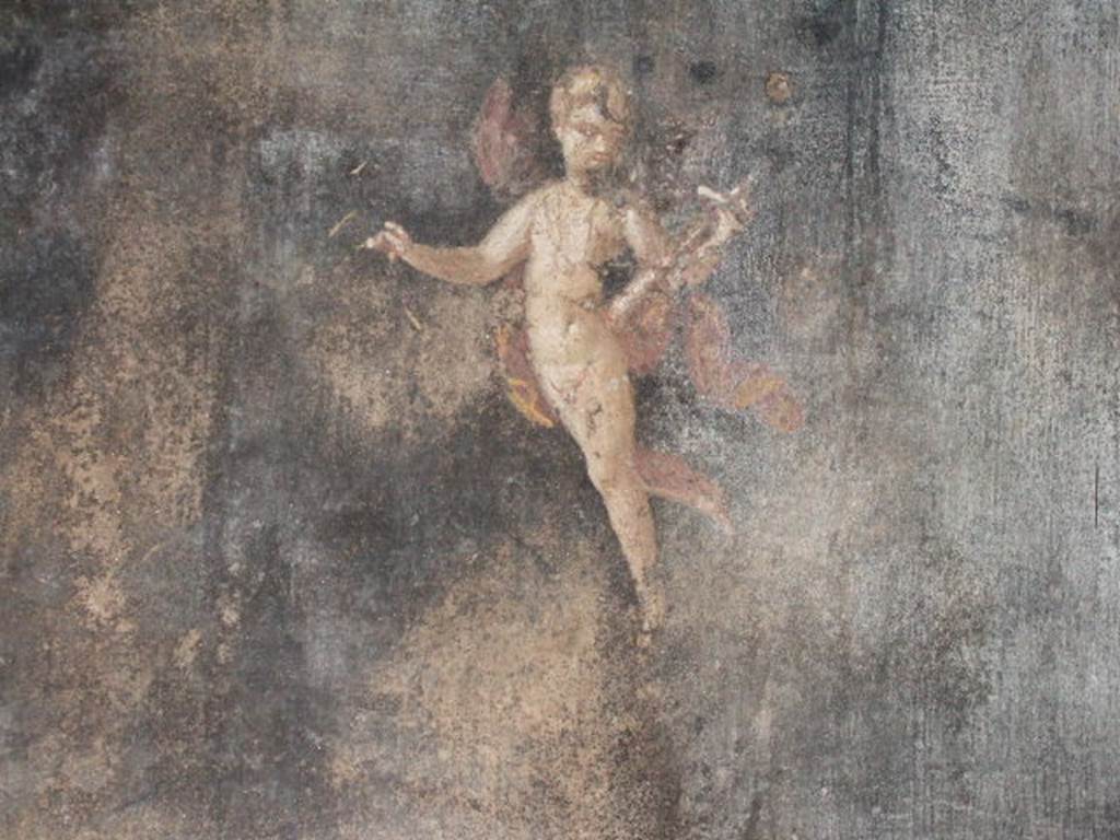 II.3.3 Pompeii. December 2005. Room 6, south wall of triclinium.
Wall painting of Amorino or flying cupid holding a baetylus (or alabaster vase) in his left hand.