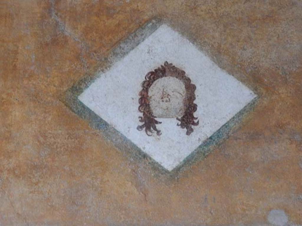 II.3.3 Pompeii. May 2016. Room 11, painted face from north end of upper west wall of west portico, above doorway to room 12. Photo courtesy of Buzz Ferebee.