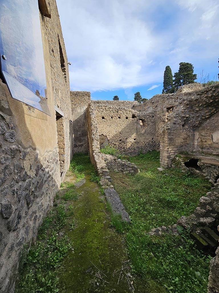 II.4.10 Pompeii. November 2024.
Looking east from entrance doorway at II.4.10, with kitchen and latrine, on right. Photo courtesy of Annette Haug.