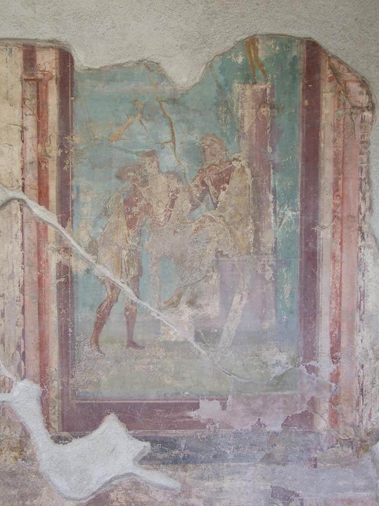 V.1.18 Pompeii. March 2009.
North wall of exedra “y”. Wall painting of The Two Fishermen Proposing a Riddle to Homer.
Homer is seated on a throne with his feet resting on a stool.
Behind him is a pillar with a gilded bronze statue on top.
On the pillar are a shield and oar, symbols of the Iliad and the Odyssey.
Further back is a ship.
In front of the poet stand two fishermen, speaking to him.
See Leach, E.W., 2004. The Social Life of Painting in Ancient Rome and on the Bay of Naples. Cambridge UK: Cambridge UP. (p.135).