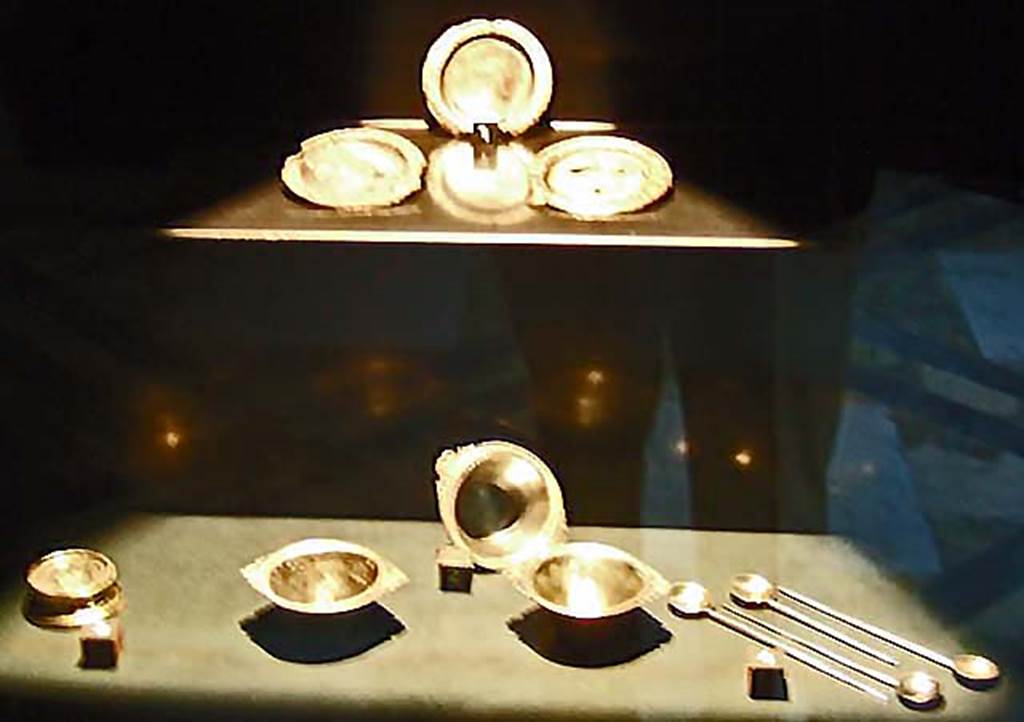 V.1.18 Pompeii. Silver found in the ala “e”.
Now in Naples Archaeological Museum.
Top left to bottom right:-
Three small saucers with traces of gilding. Inventory numbers 110850, 110851, 110852.
Round gilded base. Inventory number 110865.
Three round conical bodied cups. Inventory numbers 110853, 110854, 110855.
Four spoons (cochlearia). Inventory numbers 110857, 110858, 110859, 110860.