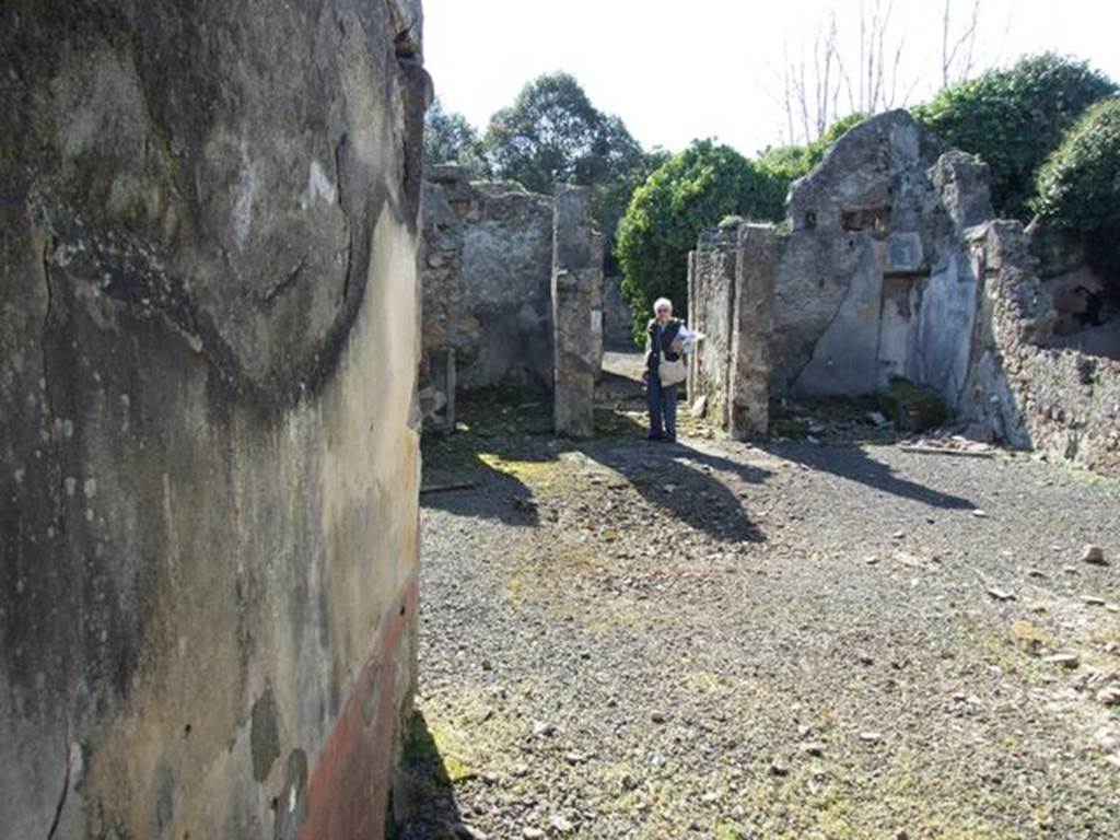 V.4.c Pompeii. March 2009. Room G, south wall of tablinum, on left. Looking west across atrium to entrance corridor fauces A. According to Sogliano, the two pillars of the fauces on the west side of the atrium were painted in yellow. However, this colour was only preserved in the pillar to the left, having mostly changed to red on the right pillar because of the oxidation of colors due to the fire that developed at the time of the catastrophe. The surface of the latter pillar was wider, and found in the centre was a painting representing a flying Swan with a ribbon between its feet and beak. See Notizie degli Scavi, 1905, (p.131). Note: Sogliano would have probably been describing the “wider” pillar on the right, as the wider pillar on the left in our photo.