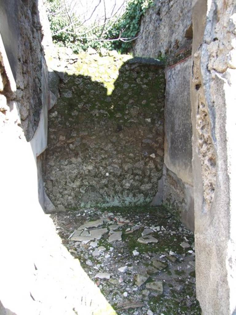 V.4.c Pompeii. March 2009. Room H, looking east. Doorway to cubiculum on south side of tablinum. On the right of this doorway the painting of Mercury was discovered, on a large red panel. See the description on the photo entitled “Looking east across north side of atrium, room B” in Part 1. According to Sogliano, the doorway had a threshold of lava, and showed the remains of wood and raw plaster in the doorjambs. The room was divided into two parts. The rear part destined to contain the bed, which had its recess in the north wall, with the attic floor above rather low, so as to be almost an alcove.
The front part of the room had a higher ceiling. The decoration had a white background, separated into panels, with the base of the wall painted black. In the panels, flying animals could be seen, i.e. on the rear east wall two parrots with long ribbon between the beak and feet. On each of the two side walls were two swans and a flying stag, and on the wall at the entrance a ram. The floor was of cocciopesto. At the top of the south wall were the remains of a window and at a distance from it a rectangular niche that belonged to the room above.
Found on 15th March 1902 gathered together in the upper part of a room near the tablinum, a bronze statuette of Hercules with club and the apple of the Hesperides, together with the other objects described in NdS, page 213. See Notizie degli Scavi, 1905, (p.134).