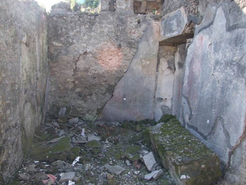 V.4.c Pompeii. March 2009. Room C, anteroom on north side of entrance corridor. Looking west into anteroom to large triclinium (doorway on right), in north-west corner of atrium.
When discovered, each painted wall of room C was divided into three panels, the centre panel was red and the side panels were black. There were also two horizontal bands, adorned with stylized flowers, which divided the panels from the base of the walls which were painted red, without decoration. In the horizontal bands, decorative objects were suspended from white ribbons, a tambourine in the centre, and two pan-pipes at the sides.
The holes for the beams at the top of the west wall (just visible in photo) showed that the room had been covered by an upper floor. In this room C, on the 1st May 1902, four skeletons with gold and silver coins and other precious objects, were found, described in NdS, 1902, page 276 and 372. See Notizie degli Scavi, 1905, p.131-2.